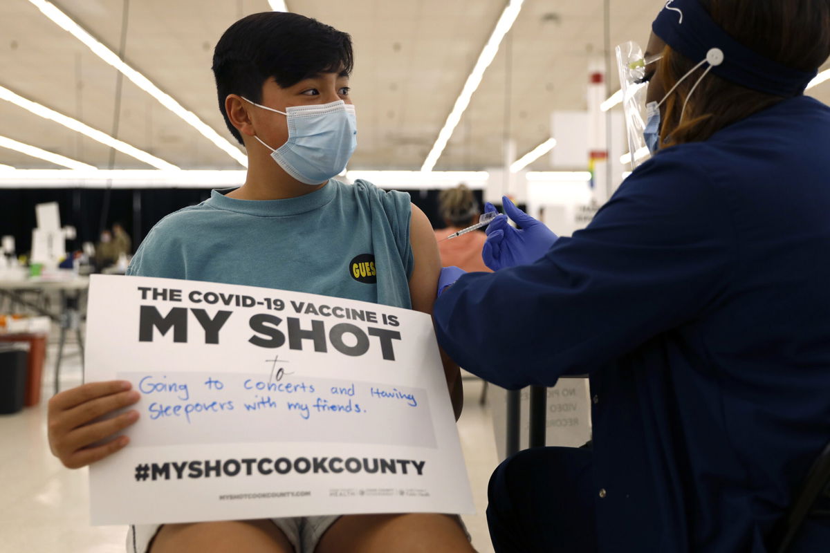 <i>Shafkat Anowar/AP</i><br/>A teenager holds a sign in support of Covid-19 vaccinations as he receives his first Pfizer dose in May 2021 in Des Plaines