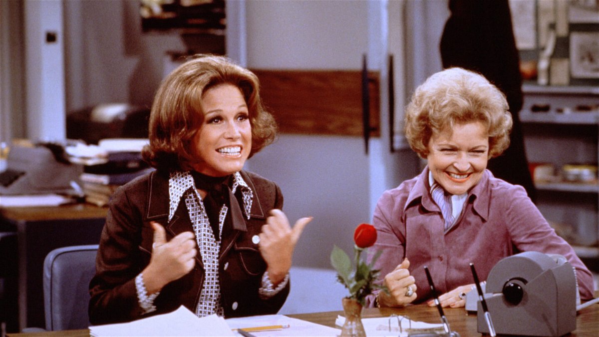 <i>CBS Photo Archive/Getty Images</i><br/>American actress Mary Tyler Moore (as Mary Richards) (left) gives a 'thumbs up' sign as she sits at her desk with Betty White (as Sue Ann Nivens) in a scene from 'The Mary Tyler Moore Show' in 1975.