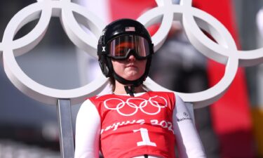 United States ski jumper Anna Hoffman standing in front of Olympic rings with helmet on