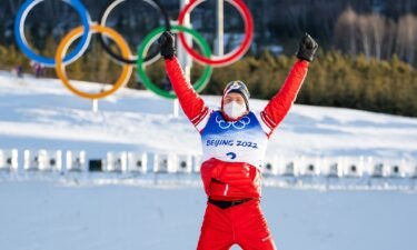 Alexander Bolshunov jumping on the podium after winning men's skiathlon