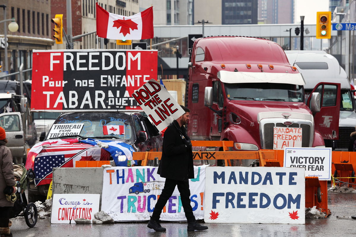 <i>DAVE CHAN/AFP/AFP via Getty Images</i><br/>A protester walks in front of parked trucks in Ottawa as demonstrations continue over vaccine mandates and coronavirus restrictions on February 8.