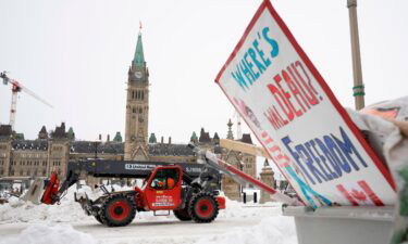 Machinery moves a concrete barricade past the Parliament buildings and a container of garbage from the trucker protest which has occupied the streets of Ottawa