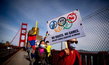 Protesters hold up signs while marching across the Golden Gate Bridge during a demonstration against the 2022 Beijing Winter Olympics in San Francisco