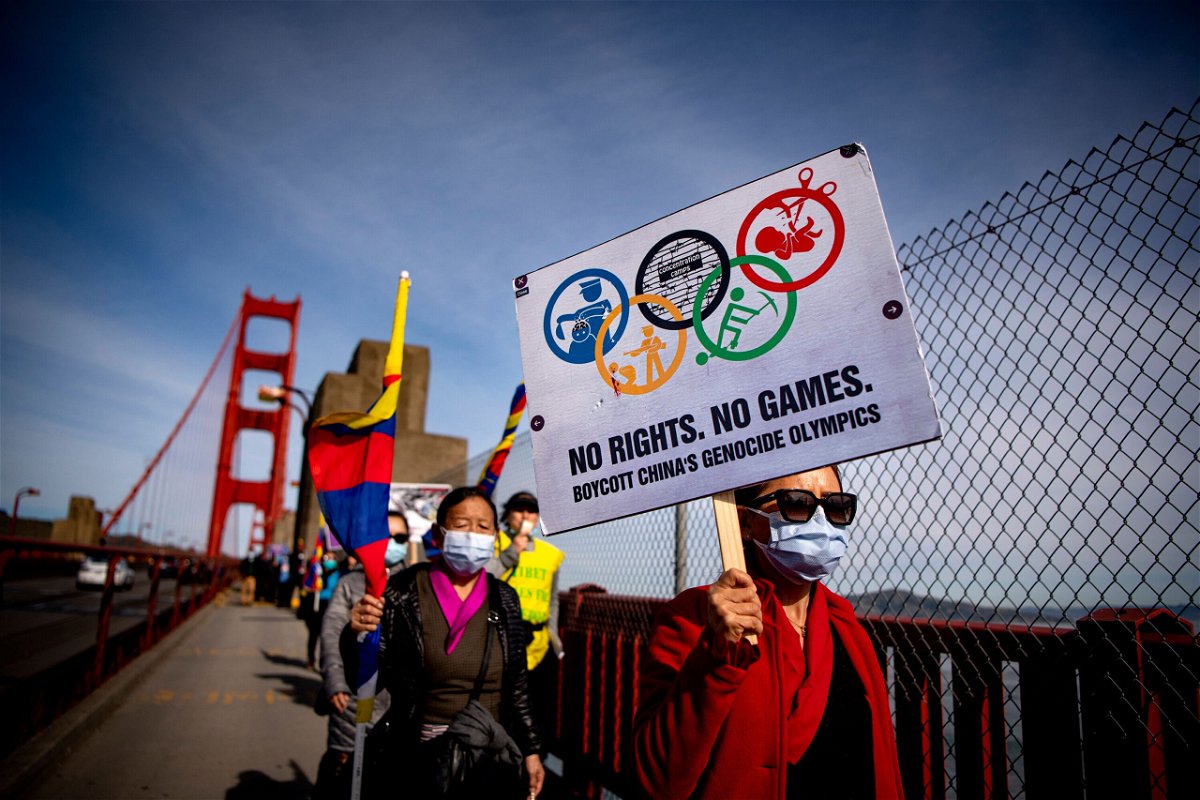 Protesters hold up signs while marching across the Golden Gate Bridge during a demonstration against the 2022 Beijing Winter Olympics in San Francisco