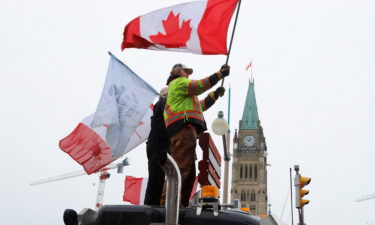 People wave flags on top of a truck in front of Parliament Hill on Sunday as truckers and their supporters continue to protest against the Covid-19 vaccine mandates in Ottawa.