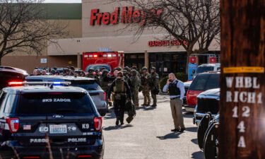 Emergency responders gather at the store as the hunt for a suspect continued Monday.