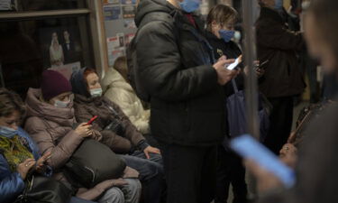 Commuters look at their phones as they travel in a local train in Kyiv