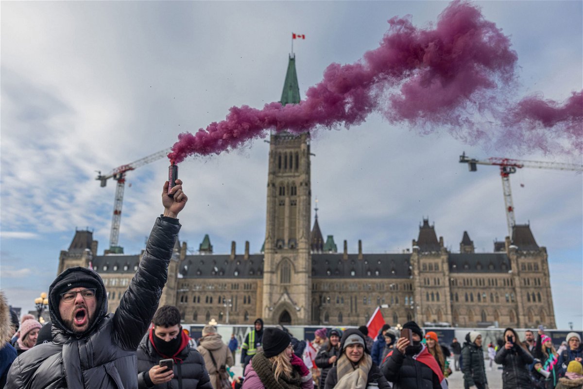 <i>Alex Kent/Getty Images</i><br/>A man yells while holding a smoke firework during a protest against a Covid-19 vaccine mandate on Parliament Hill in Ottawa on Saturday.