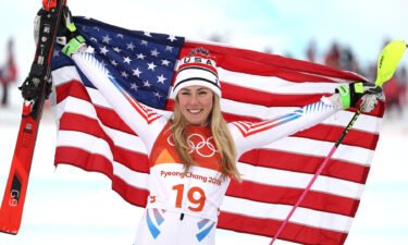 Mikaela Shiffrin holds up an American flag while celebrating at the 2018 Olympics