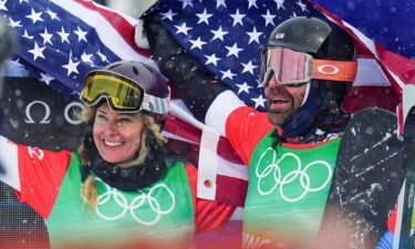 Lindsey Jacobellis and Nick Baumgartner hold American flags up and smile in celebration