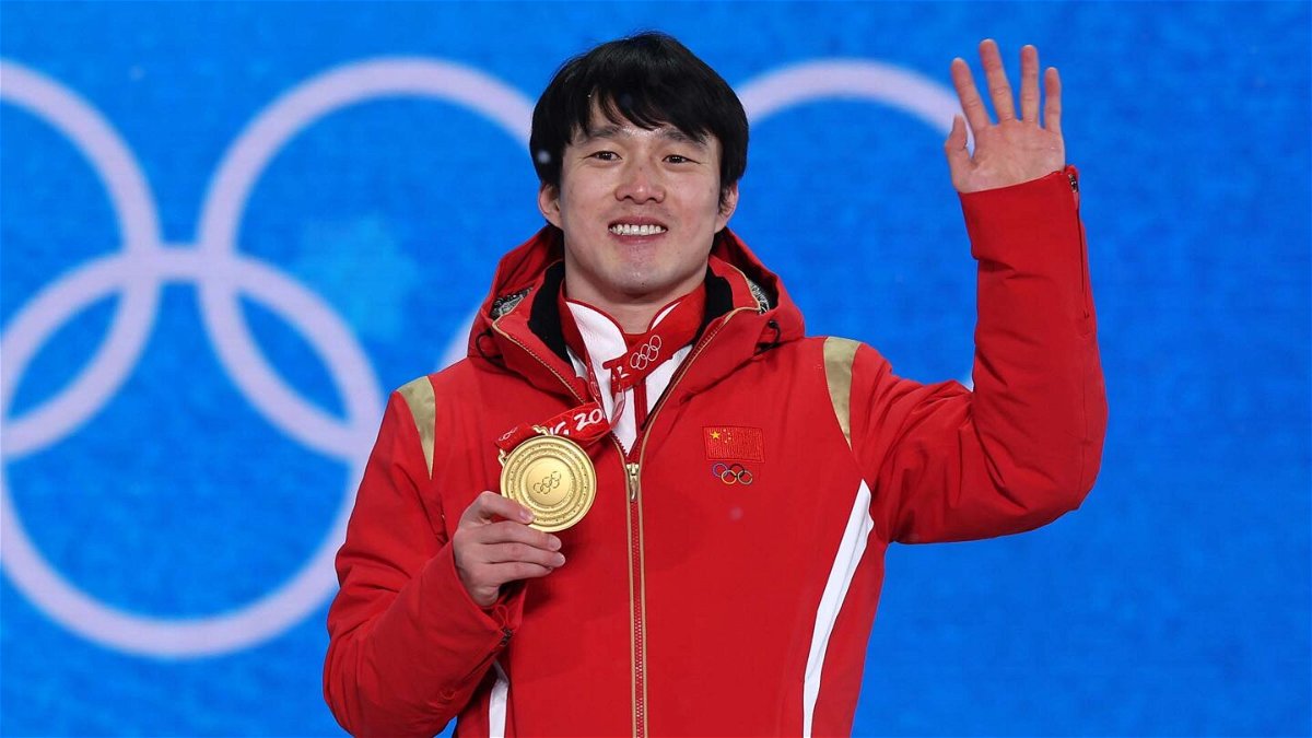 Qi Guangpu waves and holds Olympic gold medal