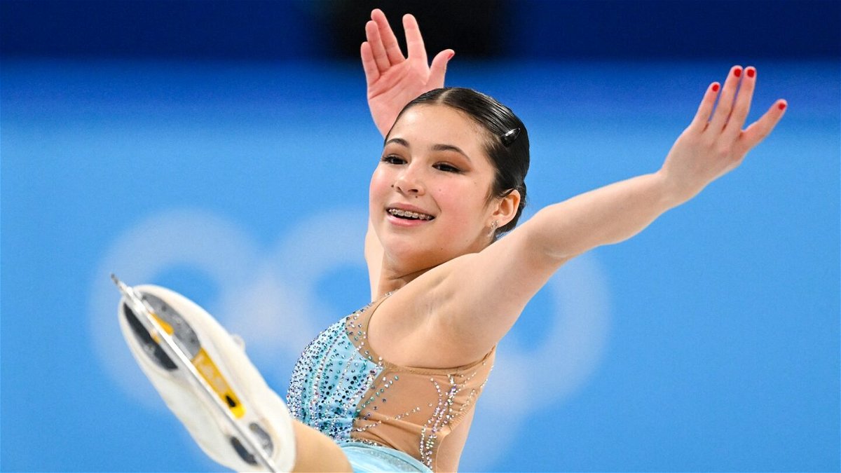 Alysa Liu in light blue skates with arms in the air and leg in the air