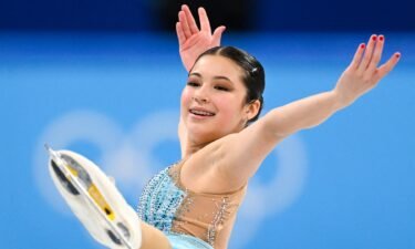 Alysa Liu in light blue skates with arms in the air and leg in the air
