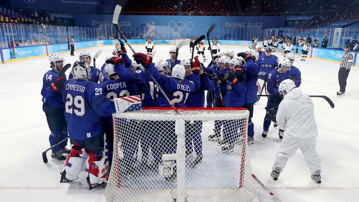 U.S. men's hockey team crowds around net and celebrates