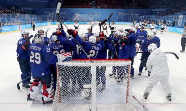 U.S. men's hockey team crowds around net and celebrates