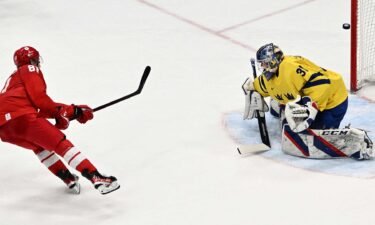 ROC men's hockey player in red shoots puck towards Sweden goalie in yellow