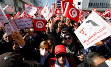 Demonstrators hold placards and Tunisian national flags during a protest March 13 in Tunis against President Kais Saied's seizure of governing powers.