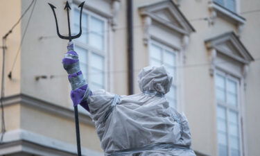 A statue of Roman god Neptune stands covered in protective plastic in Lviv's Market Square.