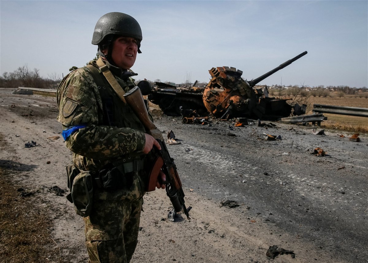 <i>Gleb Garanich/Reuters</i><br/>A Ukrainian serviceman stands near the wreck of a Russian tank on the front lines in the Kyiv region