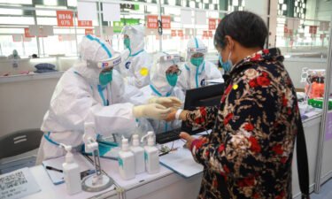 Staff members help a patient register at a designated quarantine facility in Shanghai