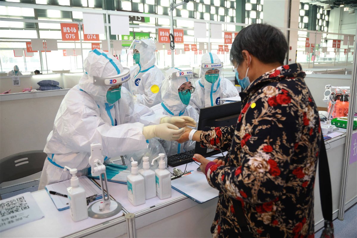 <i>CHINE NOUVELLE/SIPA/Shutterstock</i><br/>Staff members help a patient register at a designated quarantine facility in Shanghai