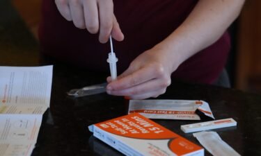 A Walmart worker processes a nasal swab in one of the new government-issued COVID-19 Antigen Rapid test kits she received as she self tests while at home on February 8