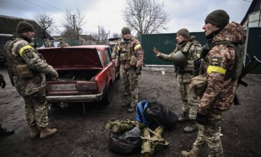 Ukrainian soldiers unload weapons from the trunk of an old car northeast of Kyiv