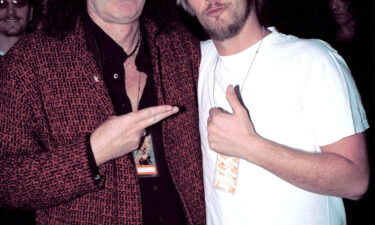 Queen guitarist Brian May (L) poses with Taylor Hawkins in January 2002. Taylor Hawkins became a drummer after being wowed by Queen drummer Roger Taylor.