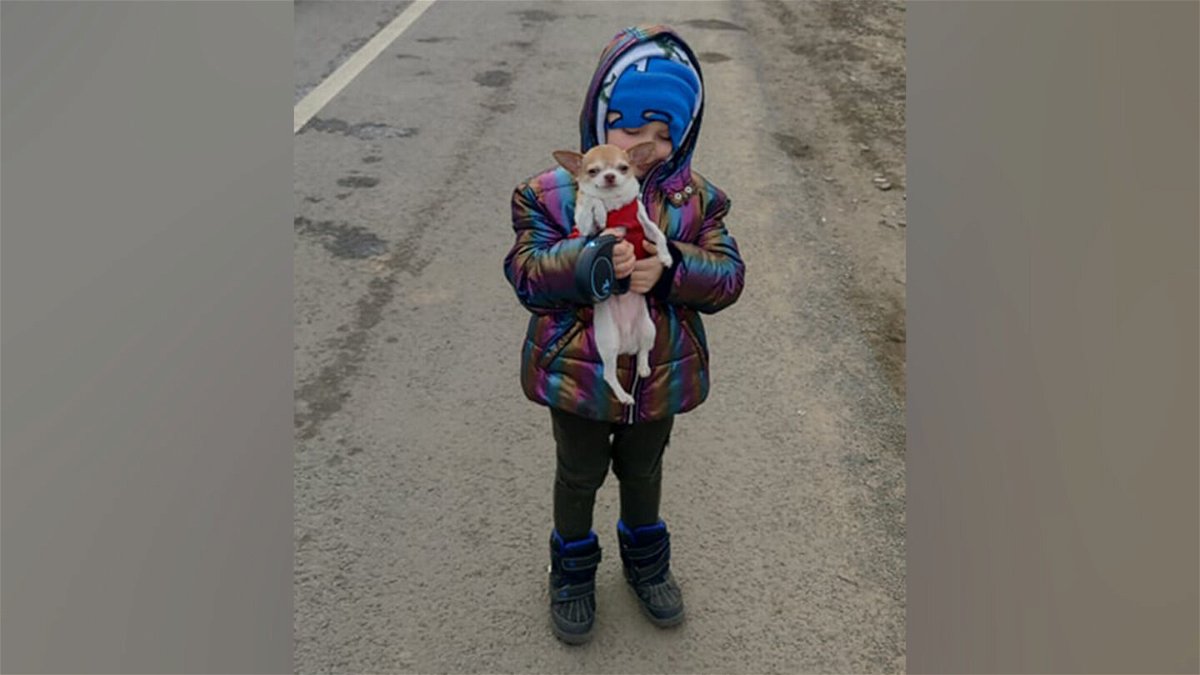 <i>Courtesy Julia Temchenko</i><br/>Five year old Milan keeps his spirits up with a friend's dog during stalemate traffic at a Poland checkpoint.