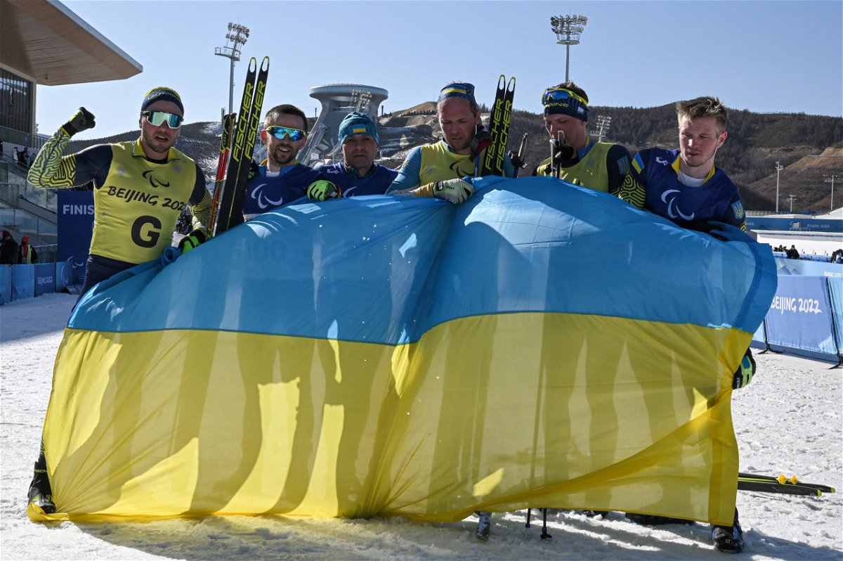 <i>MOHD RASFAN/AFP/AFP via Getty Images</i><br/>Ukrainian athletes celebrate with their country's flag after winning the mens middle distance vision impaired para biathlon.