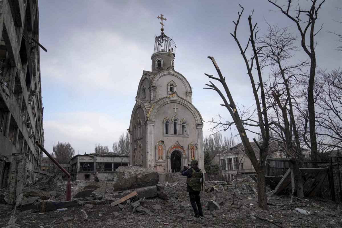 <i>Evgeniy Maloletka/AP</i><br/>A Ukrainian serviceman takes a photograph of a damaged church after shelling in a residential district in Mariupol