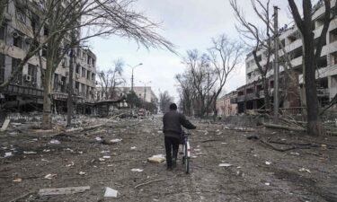 A man is seen walking with a bicycle in a street damaged by shelling in Mariupol