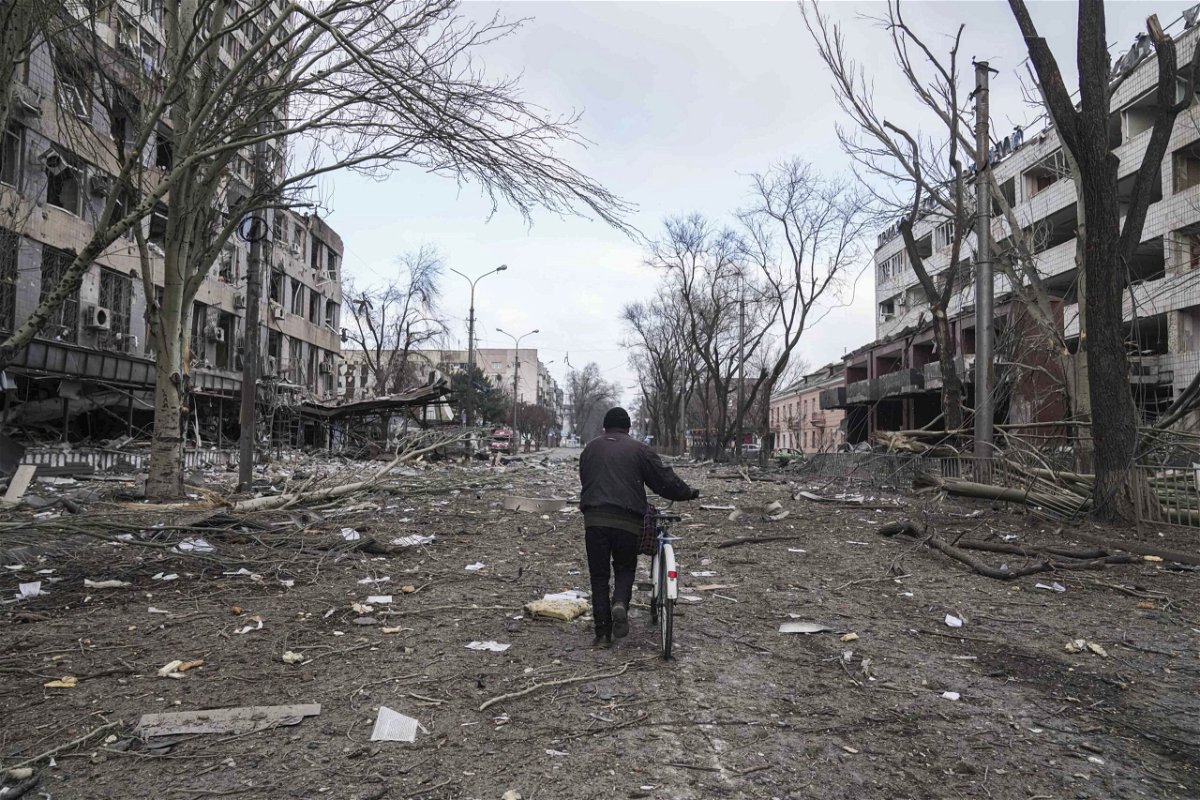 <i>Evgeniy Maloletka/AP</i><br/>A man is seen walking with a bicycle in a street damaged by shelling in Mariupol