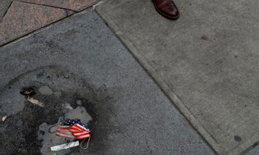 A protective face mask imprinted with the U.S. flag lays on the ground.