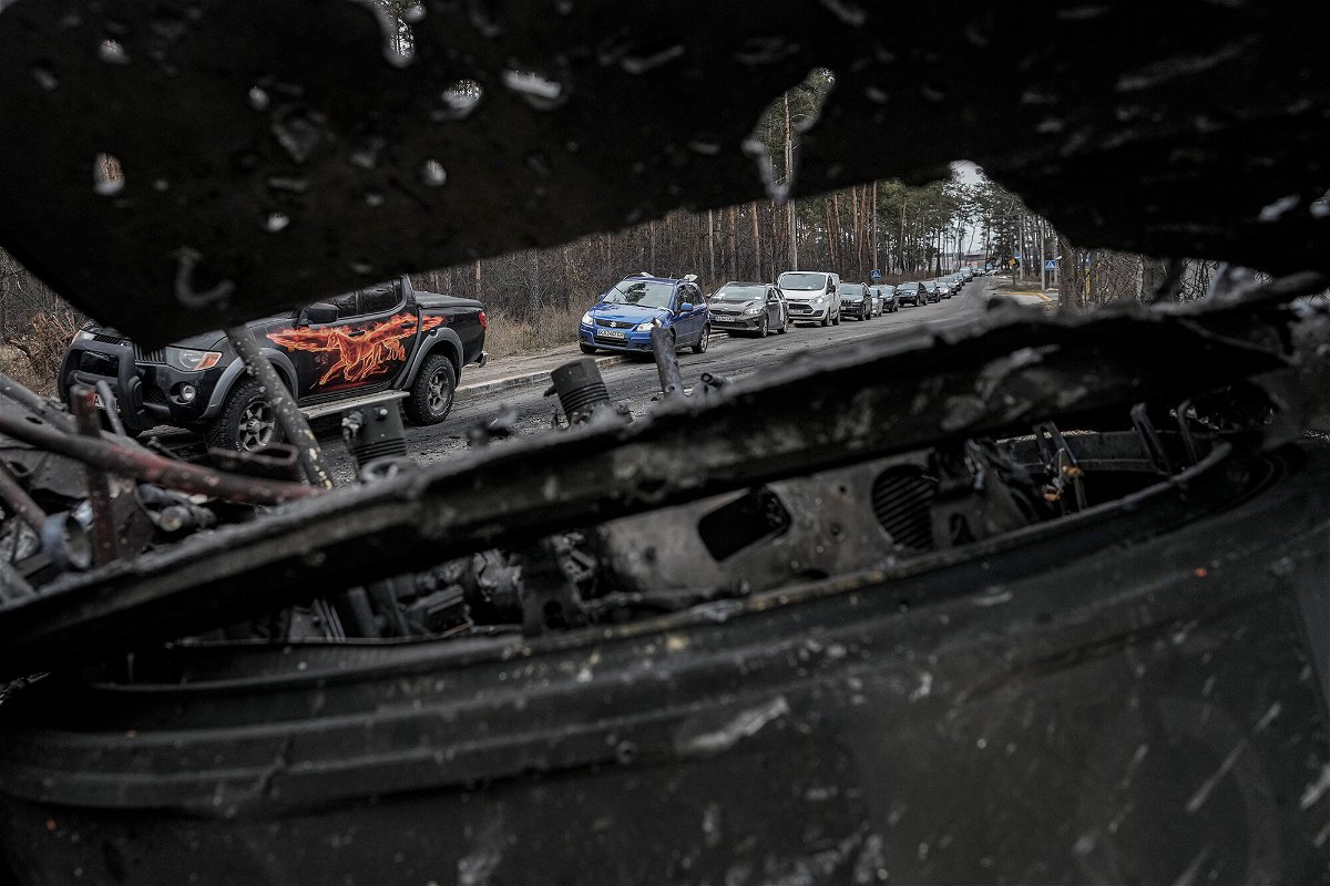 <i>Vadim Ghirda/AP</i><br/>Cars drive past a destroyed Russian tank as a convoy of vehicles evacuating civilians leaves Irpin