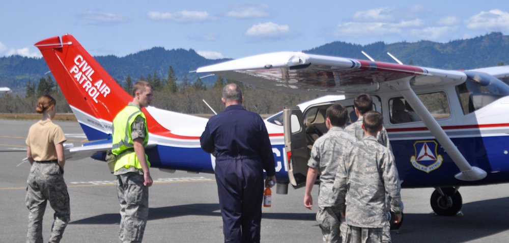 Pilot Maj Mike Wissing (blue flight suit) shows cadets features of the Cessna 206 aircraft as they board for Orientation Rides