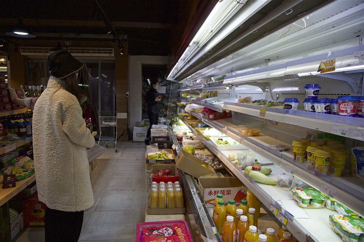 <i>Chen Si/AP</i><br/>A customer stands near partially emptied shelves at a supermarket in Shanghai