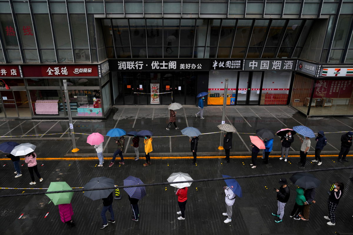 <i>Andy Wong/AP</i><br/>Locked-down residents line up in the rain for Covid tests in Beijing on April 27.