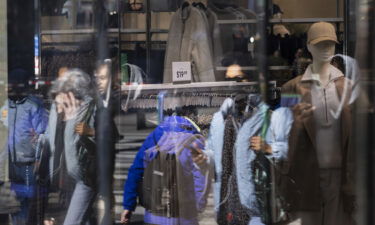 People walk past a sign showing the price of clothing in a store in New York in February.