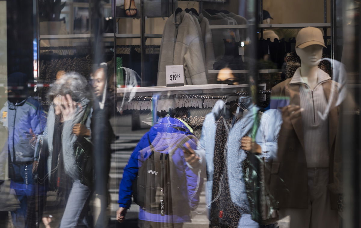 <i>Justin Lane/EPA-EFE/Shutterstock</i><br/>People walk past a sign showing the price of clothing in a store in New York in February.