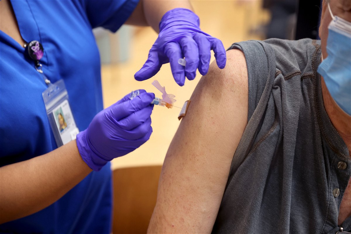 <i>Scott Olson/Getty Images</i><br/>Lalain Reyeg administers a COVID-19 booster vaccine and an influenza vaccine to Army veteran Gary Nasakaitis at the Edward Hines Jr.