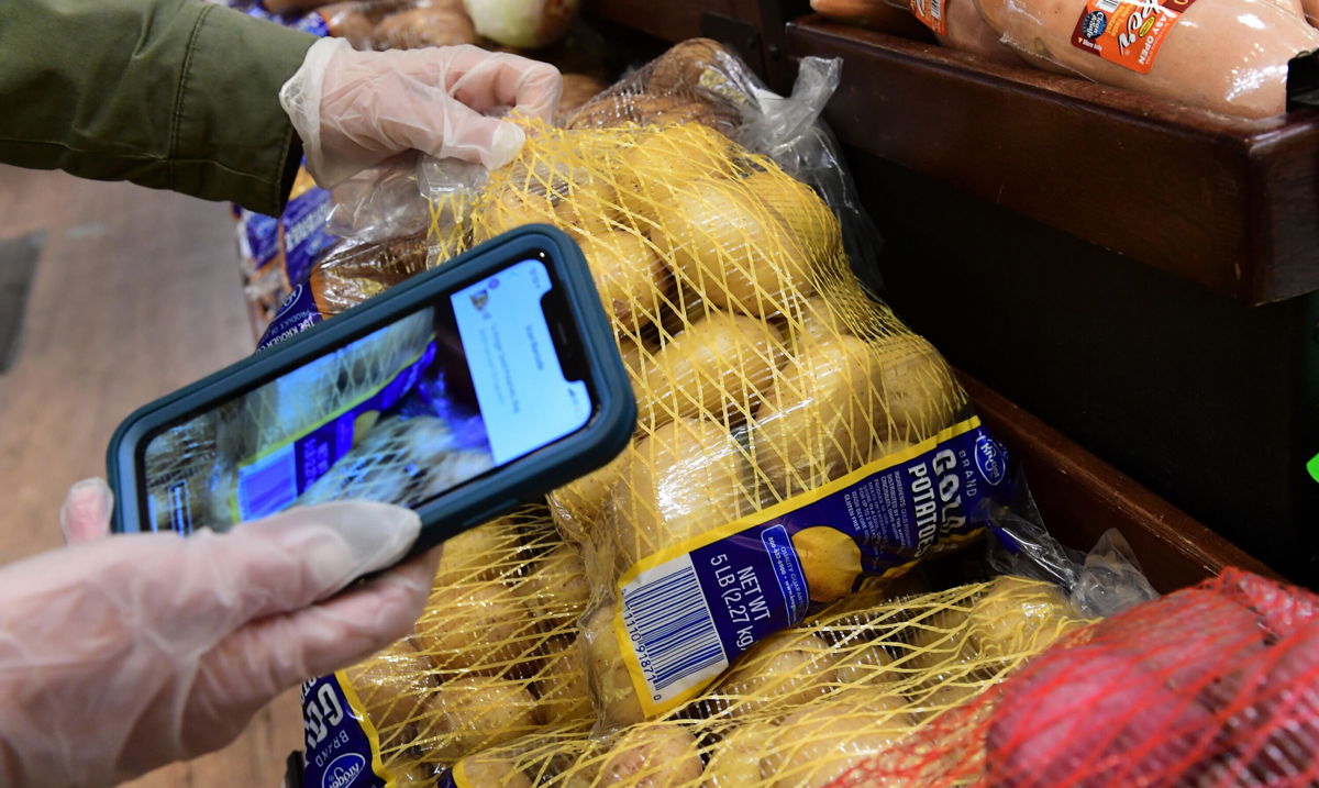 <i>Frederic J. Brown/AFP/Getty Images</i><br/>An Instacart employee uses her cellphone to scan barcodes showing proof of purchase for the customer while picking up groceries from a supermarket for delivery on March 19