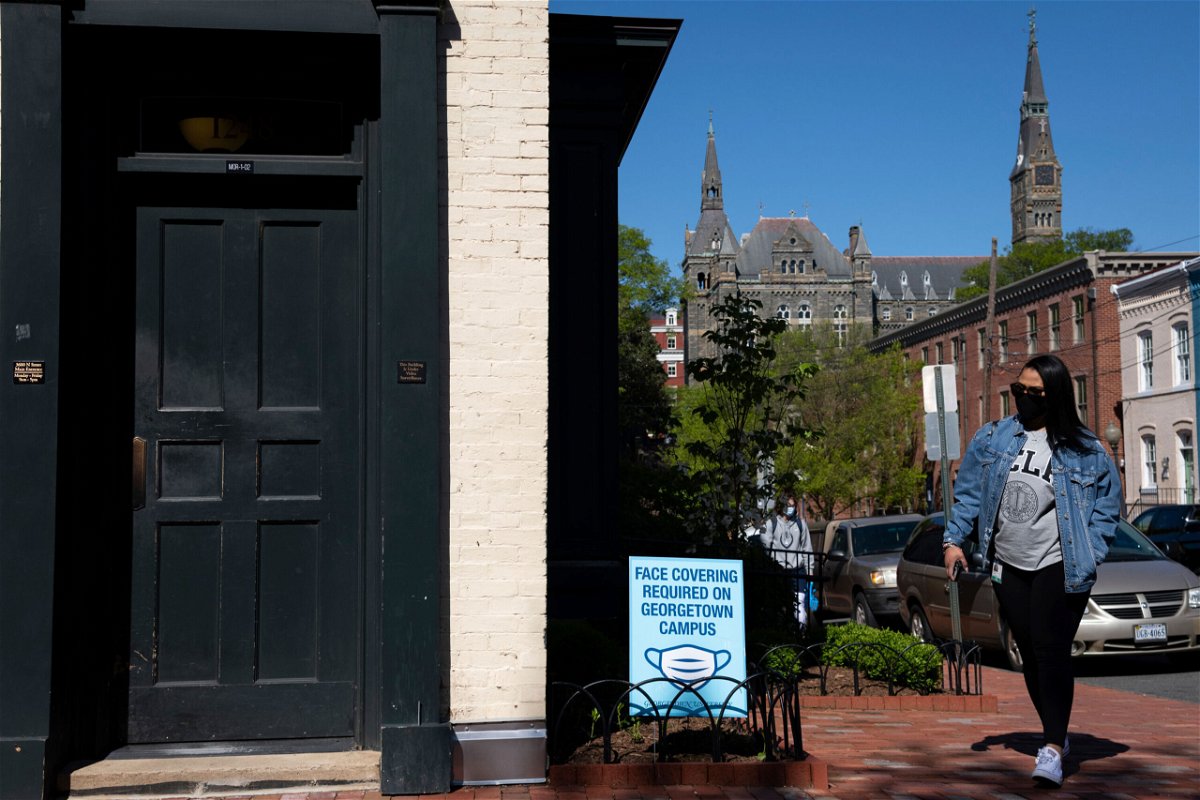 <i>Graeme Sloan/Sipa/AP</i><br/>Students walk past a face mask sign on campus at Georgetown University in Washington