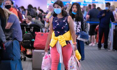 Some people continue to wear face masks this week such as these travelers at Orlando International Airport.