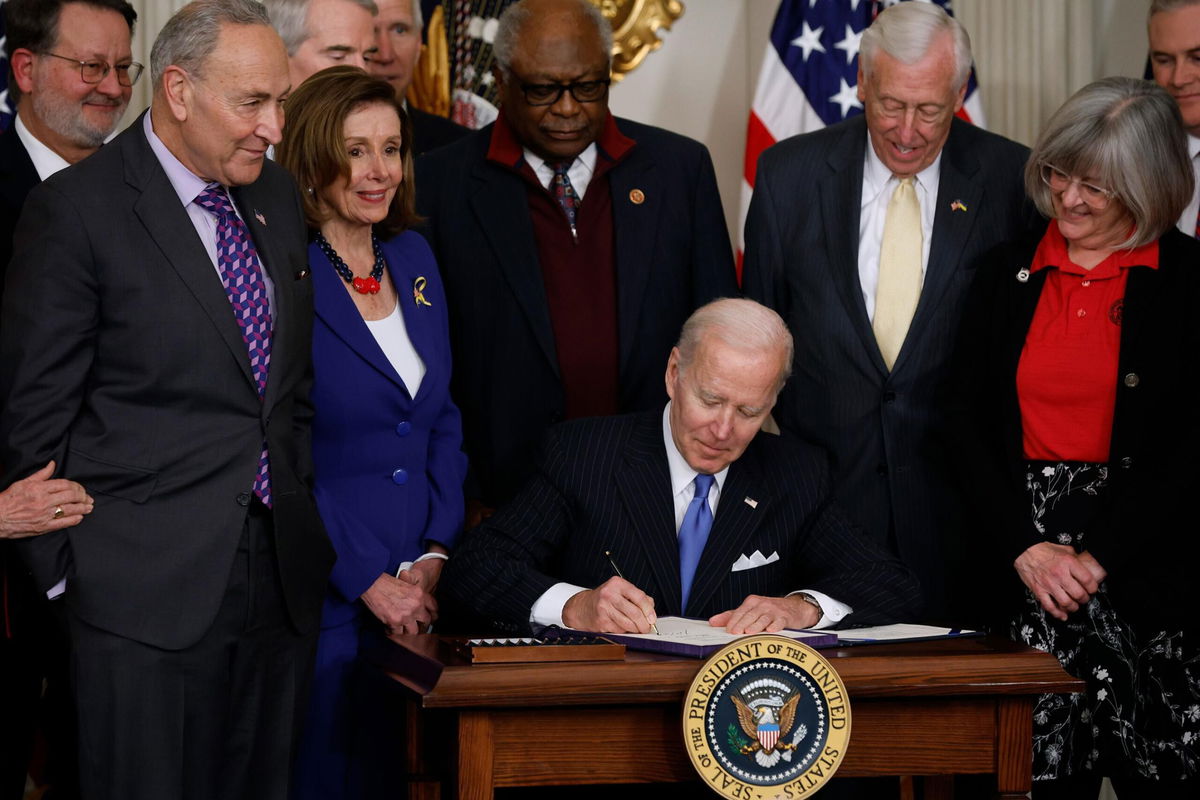 <i>Chip Somodevilla/Getty Images</i><br/>President Joe Biden signs the Postal Service Reform Act into law during an event with (from left) Sen. Gary Peters (D-MI)