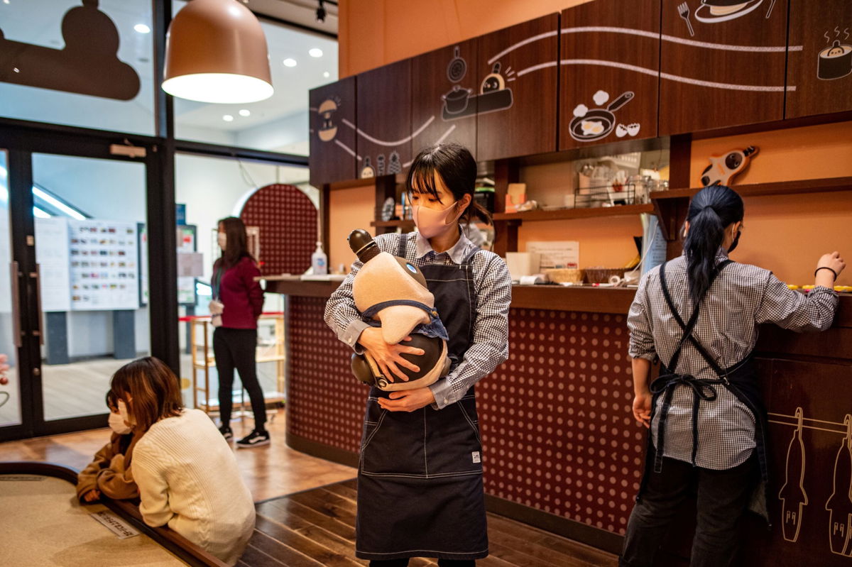 <i>PHILIP FONG/AFP/Getty Images</i><br/>A worker holding a Lovot robot at a cafe in Kawasaki