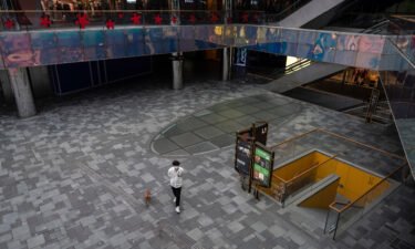 A man walks his dog through Taikoo Li mall after many retail stores were closed to help prevent the spread of COVID-19 on May 10 in Beijing