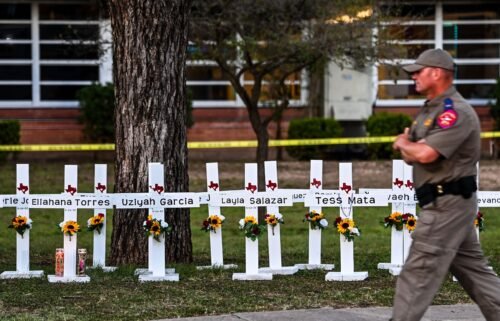 Police officers walk past a makeshift memorial for the shooting victims at Robb Elementary School in Uvalde