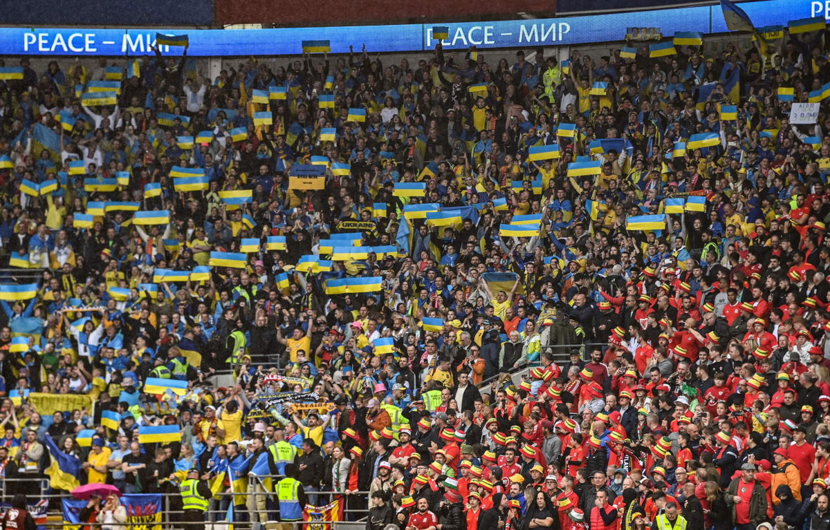 <i>PAUL ELLIS/AFP/AFP via Getty Images</i><br/>Ukraine supporters hold up their country's flag in the Cardiff City Stadium