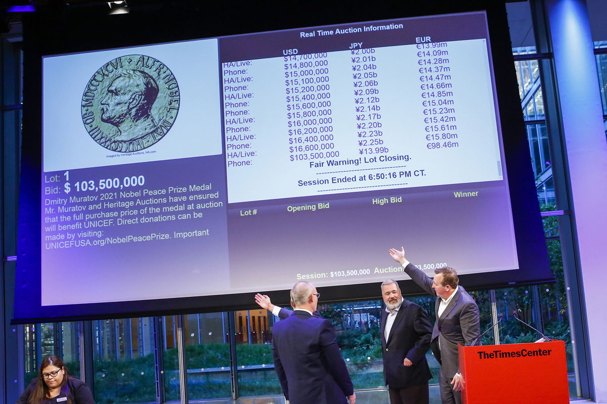 <i>Eduardo Munoz Alvarez/AP</i><br/>People point to the screen that shows the final price of $103.5 million for Russian journalist Dmitry Muratov's 23-karat gold medal of the 2021 Nobel Peace Prize after being auctioned at the Times Center